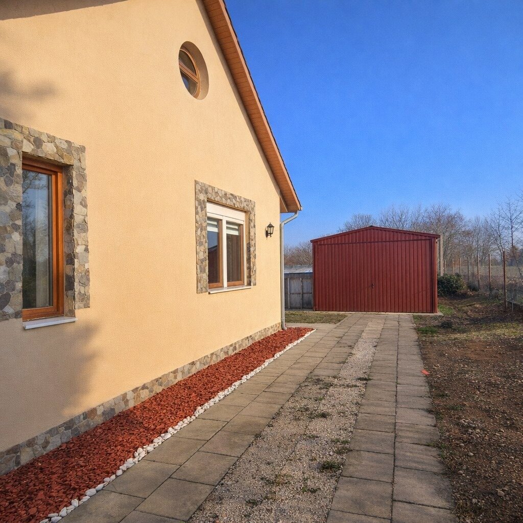 Családi ház homlokzata, sárga falak, kőburkolat, térkövezett udvar
